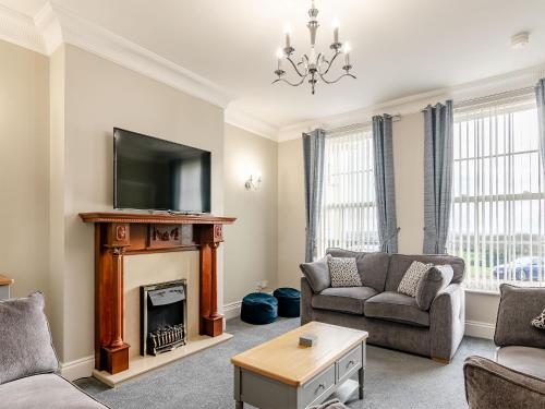 a living room with a fireplace and a tv at Wold House Cottage in Nafferton