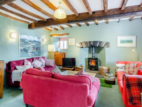 a living room with red couches and a fireplace at Thwaite Bridge Houseconiston in Coniston