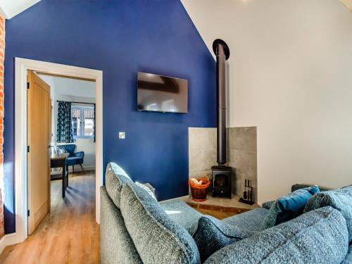 a blue living room with a couch and a fireplace at The Cowshed - Uk37349 in Hockerton