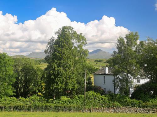 a white house in a field with trees and mountains at The Vicarage in Lowick Green