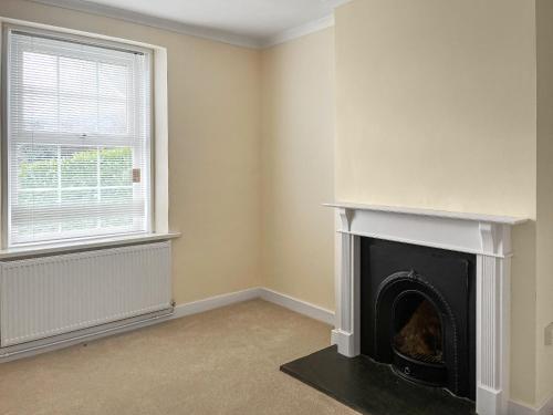 a living room with a fireplace and a window at The Farmhouse - Uk49068 in Liskeard