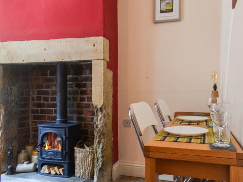a fireplace in a dining room with a table and a stove at Limestone Cottage in Hebden Bridge