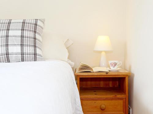 a bed with a lamp and a book on a night stand at The Dairy At Copper Beeches in Petersfield