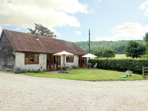 a small cottage with tables and umbrellas in the yard at The Dairy At Copper Beeches in Petersfield