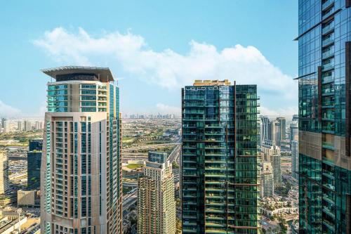 two tall skyscrapers in a city with buildings at Jumeirah Living Marina Gate - Golf & Skyline Views with Pool & Gym in Dubai