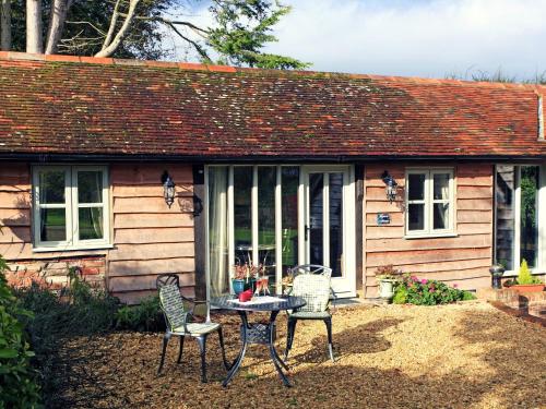 ein Tisch und Stühle vor einem Haus in der Unterkunft Alpaca Cottage in Frampton