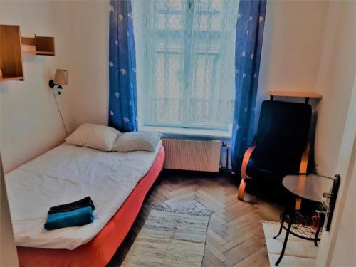 a small room with a bed and a chair and a window at Let's go back to the memories in Krakow