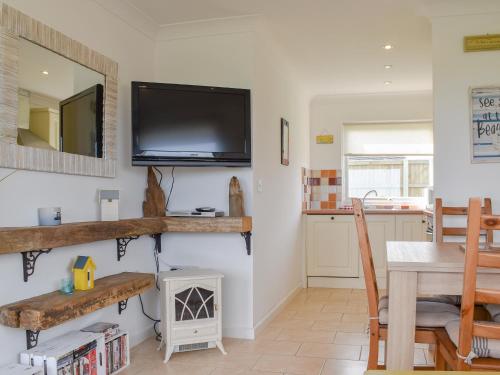 a living room with a tv on the wall and a table at On The Beach in Bacton