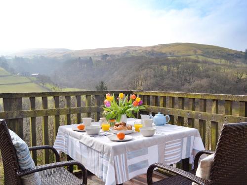 a table with a bowl of food and flowers on a balcony at Penroc in Pentre-briwnant