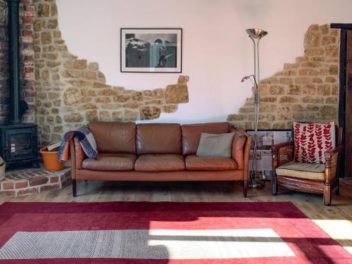 a living room with a brown couch and a chair at Feltham's Cottage - Uk42324 in Horsington