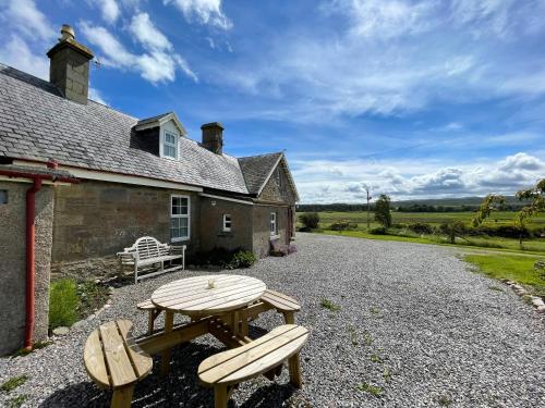 a picnic table in front of a house at Birch Cottage - Uk38992 in Dalcross