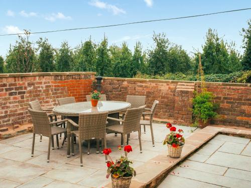a patio with a table and chairs and a brick wall at Lower House Barn in Staunton on Wye