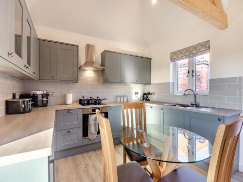 a kitchen with blue cabinets and a glass table at The Piggery - Uk37348 in Hockerton
