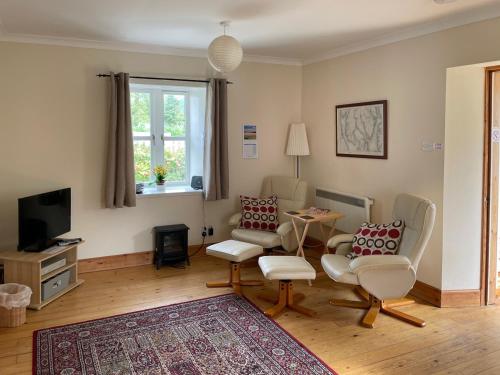 a living room with two chairs and a tv at Sanna in Ardentinny