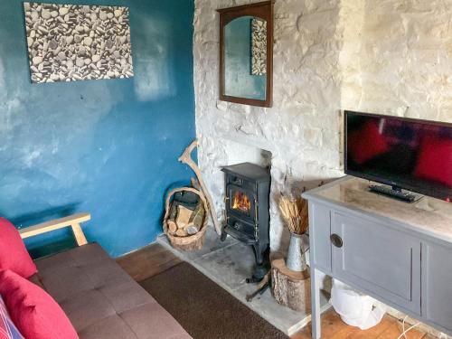 a living room with a fireplace and a tv at Y Smithy - Uk49022 in Llanybyther