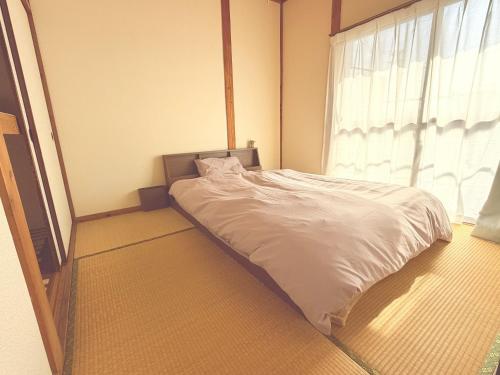 a bed in a room with a large window at Omuta Cozy Stay in Ōmuta