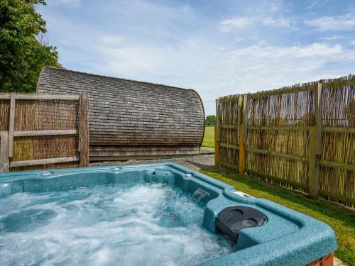 a hot tub in a yard next to a fence at Willow - Glamping Pod - Uk49947 in Oswestry