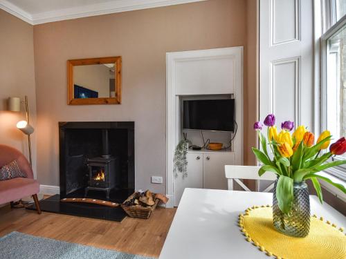 a living room with a fireplace and a vase of flowers at The Leveret in Aberlady