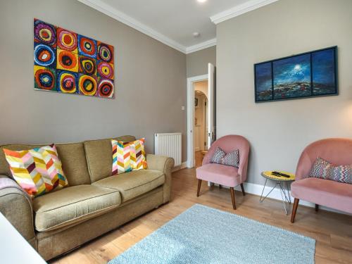 a living room with a couch and two pink chairs at The Leveret in Aberlady