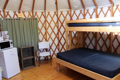 a bed in a yurt with a refrigerator and a chair at Tranquil Timbers Yurt 3 in Sturgeon Bay