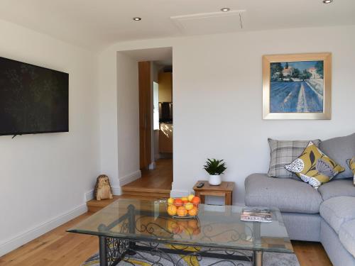 a living room with a couch and a glass table at Y Bwthyn At Tyddyn Obry in Llanfaelog