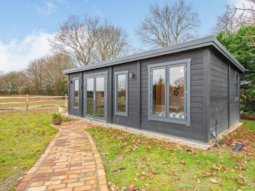 a grey shed with windows on a lawn at Holly's Hidden Hideaway - Uk36783 in Sutton Valence