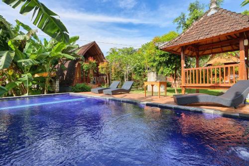 a swimming pool with chairs and a gazebo at The Tandjung Cottage in Nusa Penida