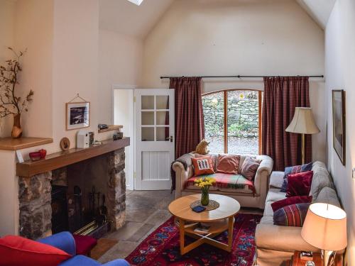 a living room with a couch and a fireplace at Gushat Cottage in Strathtay