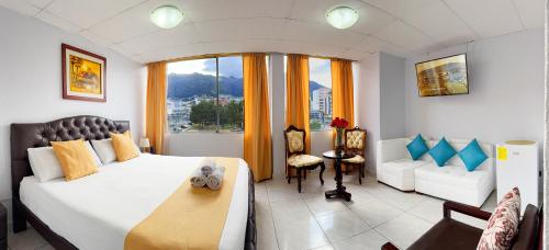 a bedroom with a bed and a couch and a window at Hotel Santamaria en quito in Quito