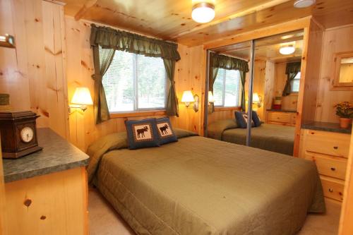 EdgertonにあるLakeland RV Campground Deluxe Loft Cabin 11のログキャビン内のベッドルーム1室(ベッド2台付)