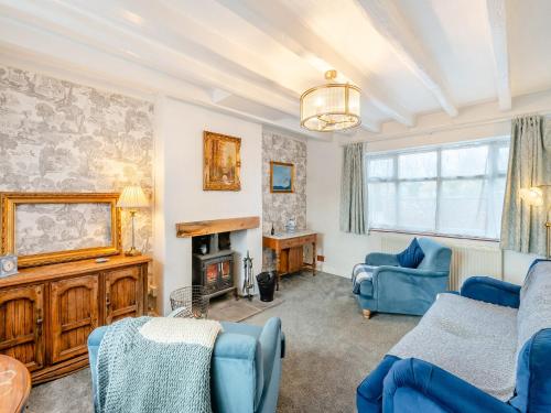 a living room with blue chairs and a fireplace at Lillie's Cottage in Sewerby