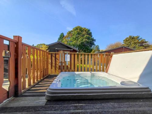 a hot tub on a deck with a wooden fence at Bowness Lodge 12 Fellside in Windermere