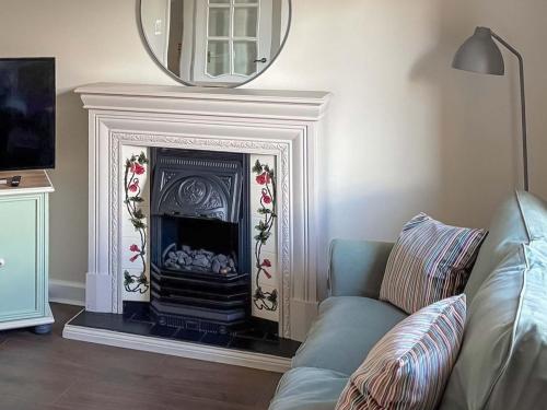 a living room with a fireplace with a mirror at India Lane Cottage in Montrose