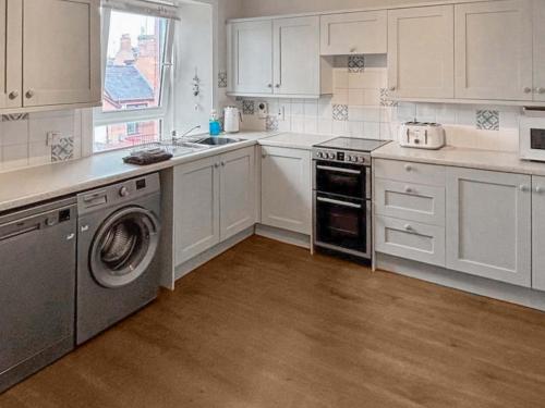 a kitchen with white cabinets and a washer and dryer at India Lane Cottage in Montrose
