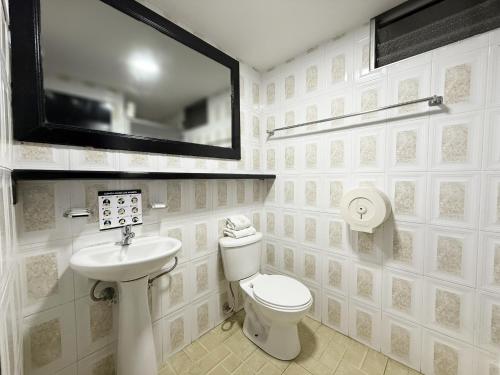a bathroom with a toilet and a sink and a mirror at Hotel Santamaria en quito in Quito
