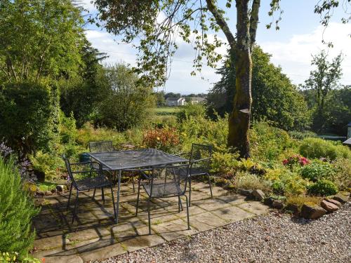 ein Tisch und Stühle stehen in einem Garten in der Unterkunft Old Steading in Brodick