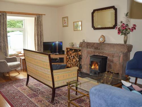 ein Wohnzimmer mit Kamin und einem Stuhl in der Unterkunft Old Steading in Brodick