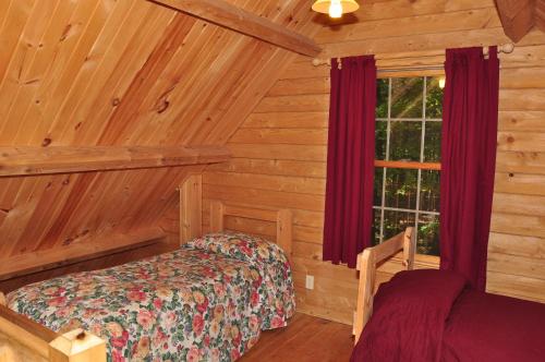 um quarto com uma cama e uma janela num chalé de madeira em Tranquil Timbers Deluxe Cabin 6 em Sturgeon Bay