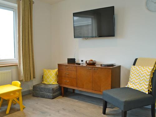 a living room with a chair and a tv on the wall at Lle Clyd in Harlech