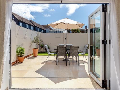 a patio with a table and chairs and an umbrella at Olive Breeze in Felixstowe