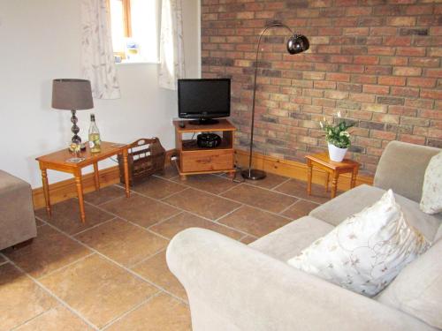 a living room with a couch and a tv at Rievaulx Cottage in Filey