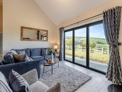 a living room with a blue couch and a large window at The Lara - Uk45019 in Mochdre