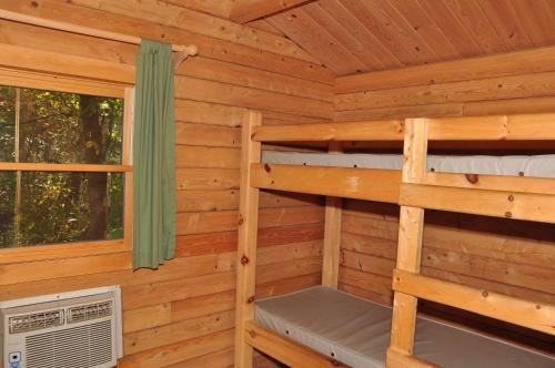 eine Blockhütte mit 2 Etagenbetten und einem Fenster in der Unterkunft Tranquil Timbers Cabin 11 in Sturgeon Bay