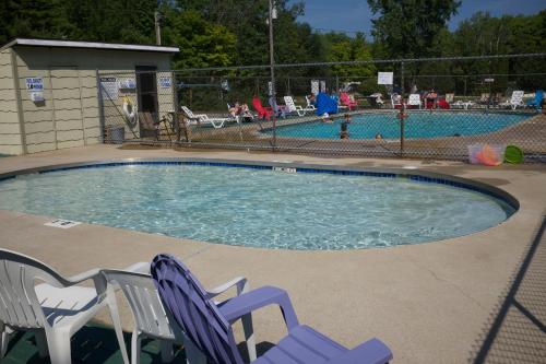 a swimming pool with two lawn chairs and a swimming pool at Tranquil Timbers Cabin 11 in Sturgeon Bay