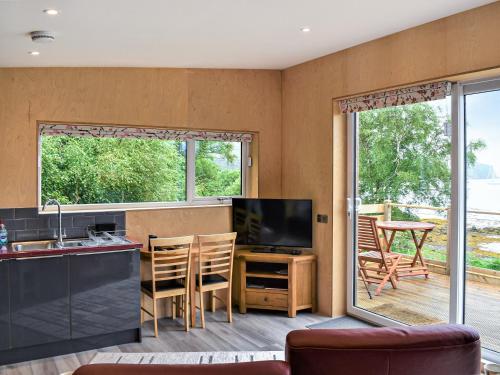 a kitchen and living room with a television and a table at The Duckling in Port na Long