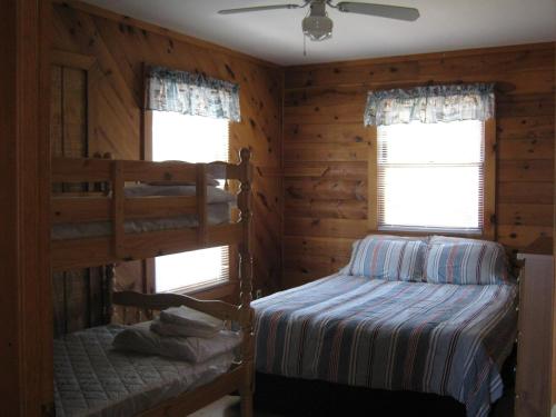 1 dormitorio con 2 literas y 2 ventanas en Virginia Landing Camping Resort Cabin 19, en Quinby