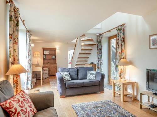 a living room with a couch and a staircase at Hopewell Barn in Hewelsfield