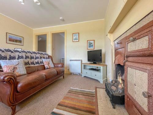 a living room with a brown leather couch and a television at Rowan Cottage - Uk38991 in Dalcross