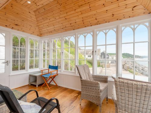 a room with windows and chairs and a table at Cliff House in Beesands