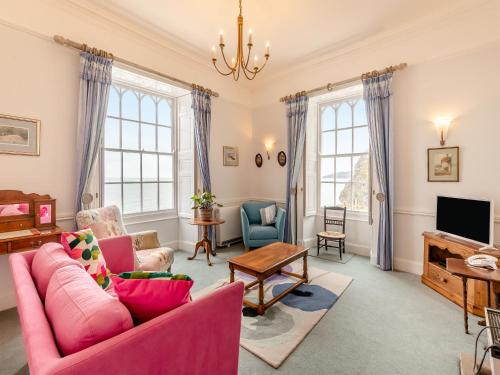 a living room with pink furniture and a tv at Cliff House in Beesands